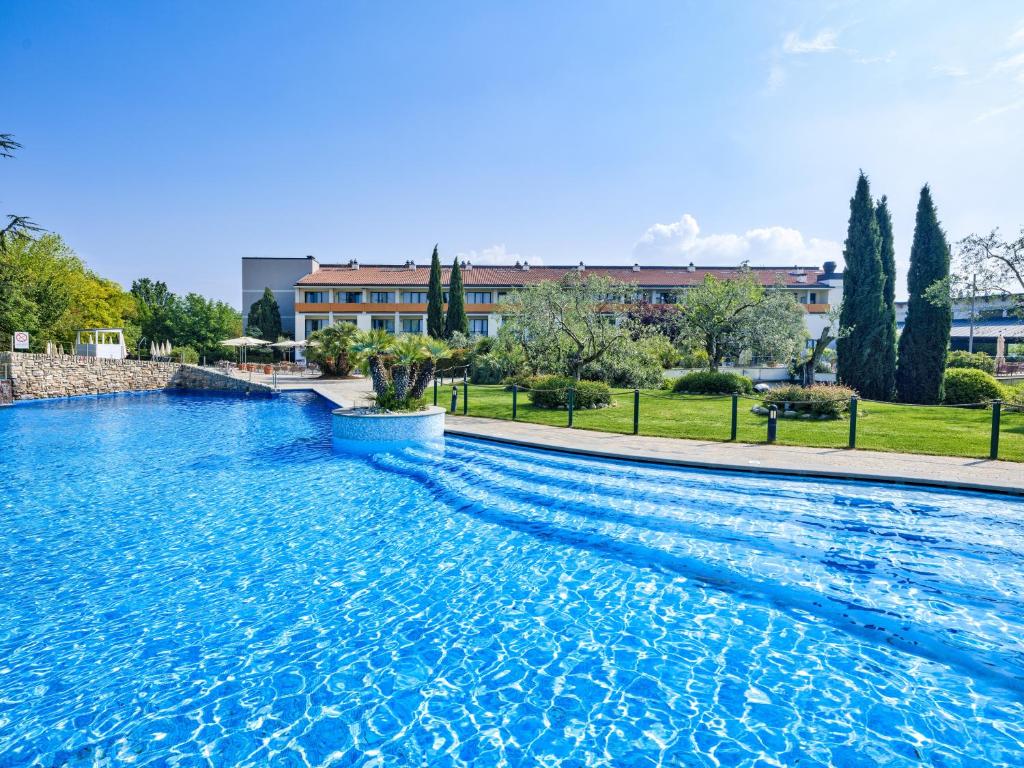 une grande piscine bleue avec un bâtiment en arrière-plan dans l'établissement Parc Hotel, à Peschiera del Garda