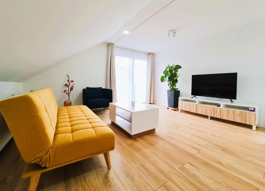 a living room with a yellow couch and a flat screen tv at Apartment Nähe Airbus in Manching