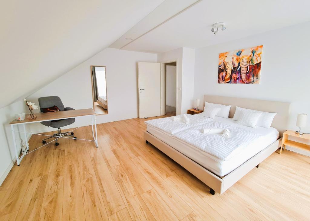 a white bedroom with a bed and a desk at Apartment Nähe Airbus in Manching