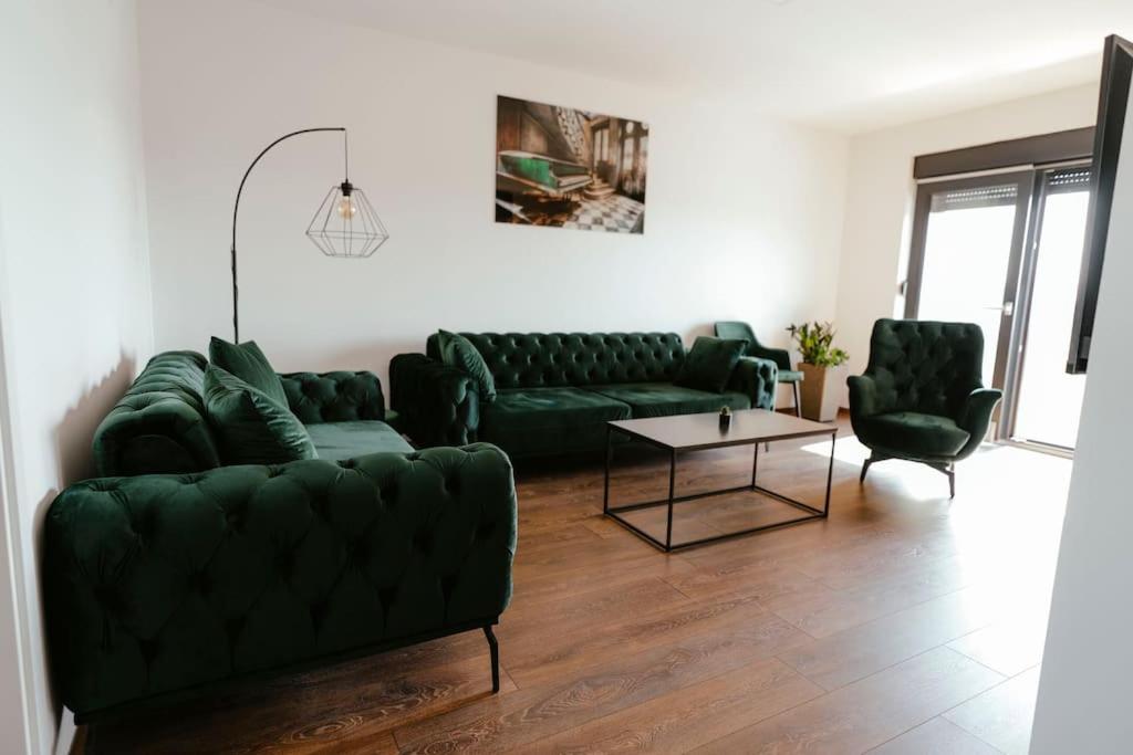sala de estar con sofás verdes y mesa en Apartman Marinela, en Belišće