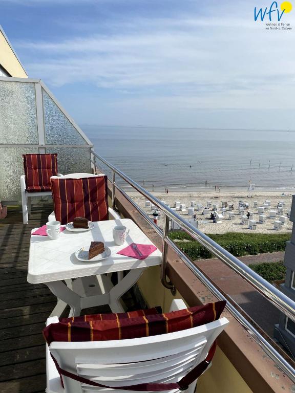 a table and chairs on a balcony overlooking the beach at Dünenschlösschen - Ferienwohnung 34 in Wangerooge