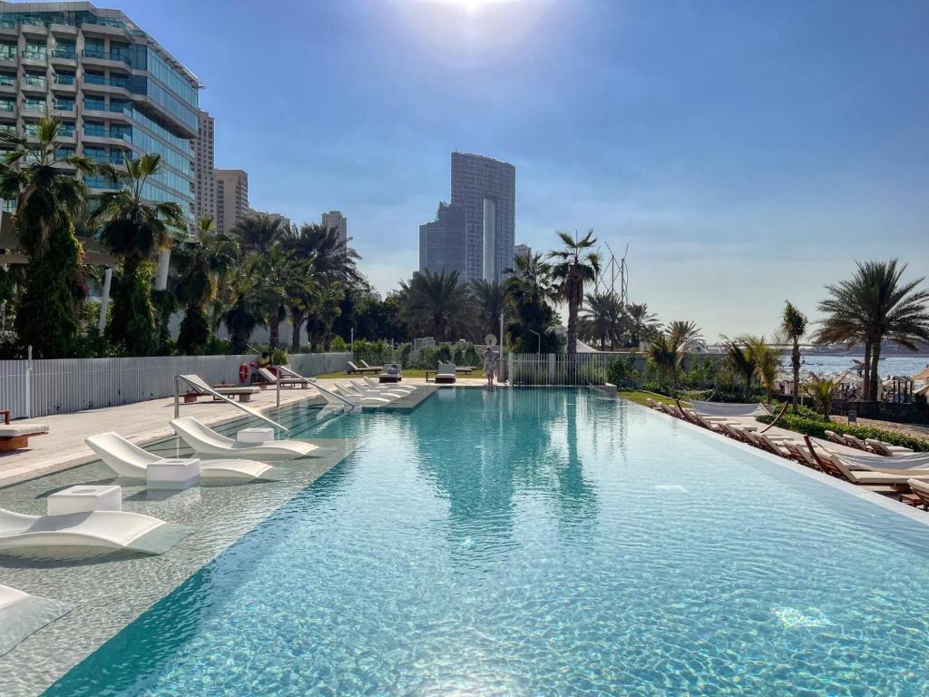 una grande piscina con sedie bianche e palme di Remarkable 2BR+storage in JBR with Sea View a Dubai