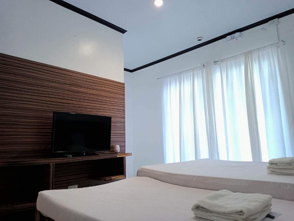 a bedroom with two beds and a flat screen tv at VILLA LOURDES RESORT in Boracay