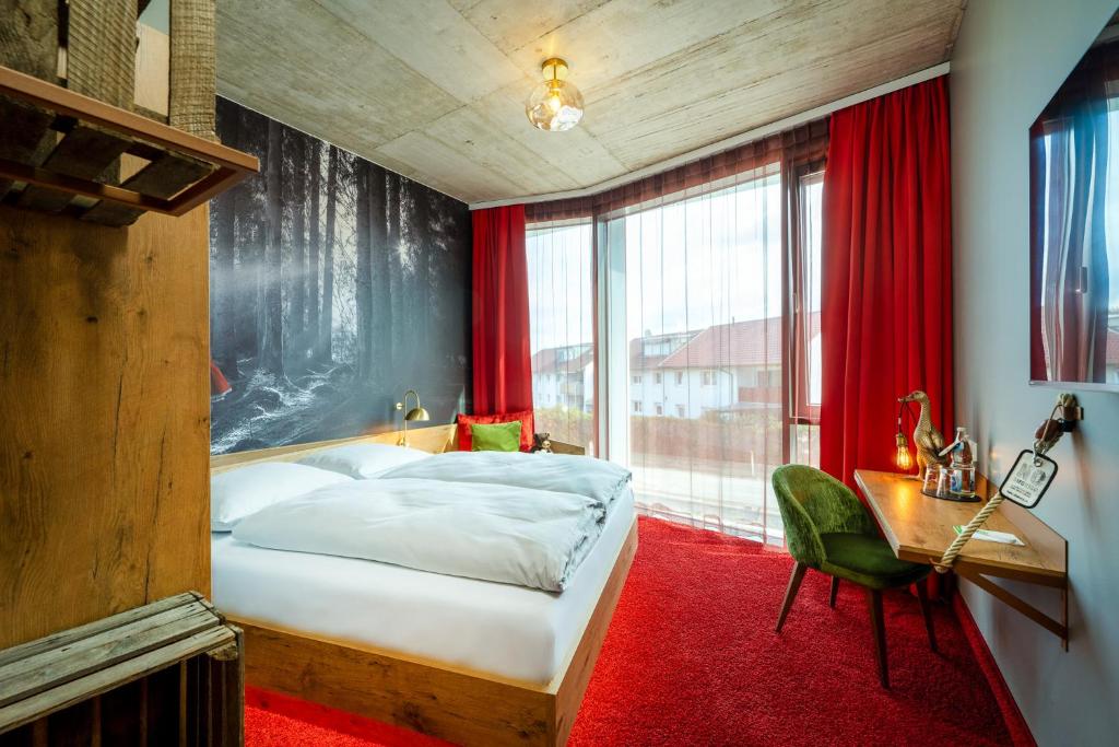 a bedroom with a bed and a desk and a window at mightyTwice Hotel Achern in Achern