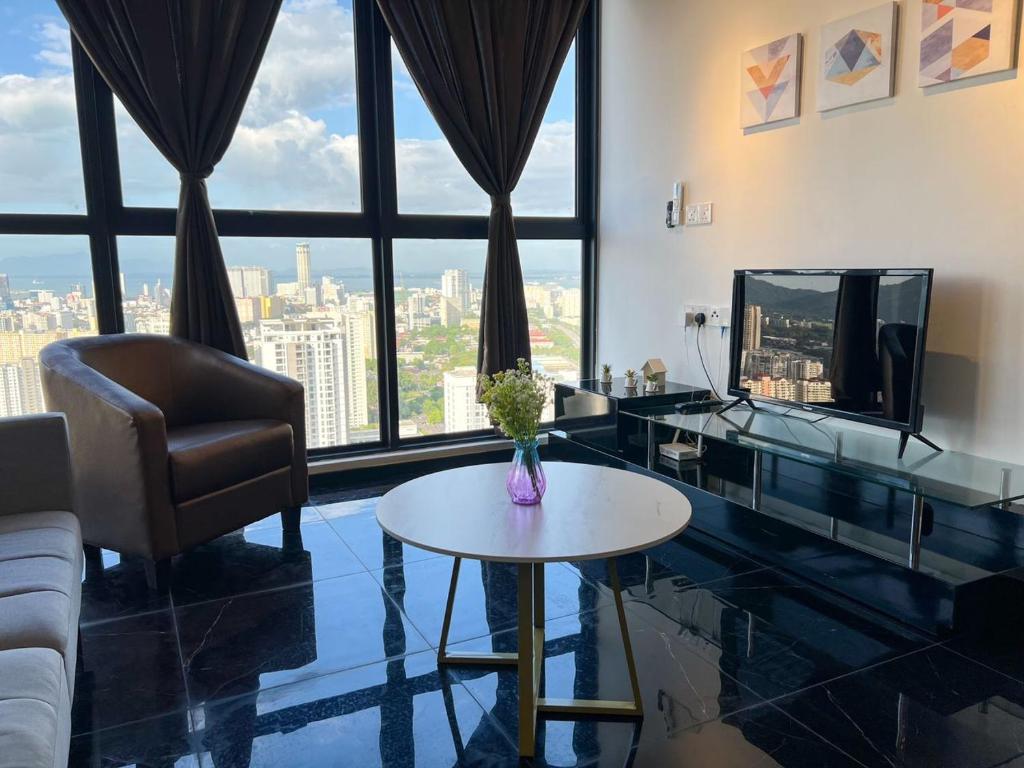 ein Wohnzimmer mit einem Sofa, einem Tisch und einem TV in der Unterkunft Georgetown City Skyline Seaview Urban Suites in Jelutong
