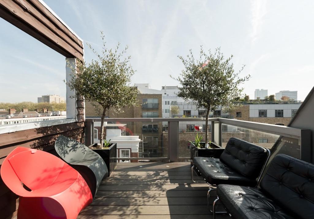 einen Balkon mit Sofas und Bäumen auf einem Gebäude in der Unterkunft Multi-Award Winning 7 Storey Home - Near Shoreditch in London
