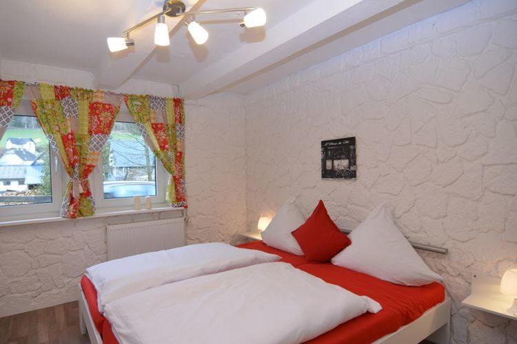 1 dormitorio con 1 cama con almohadas blancas y rojas en Haus Oberkirchen, en Schmallenberg