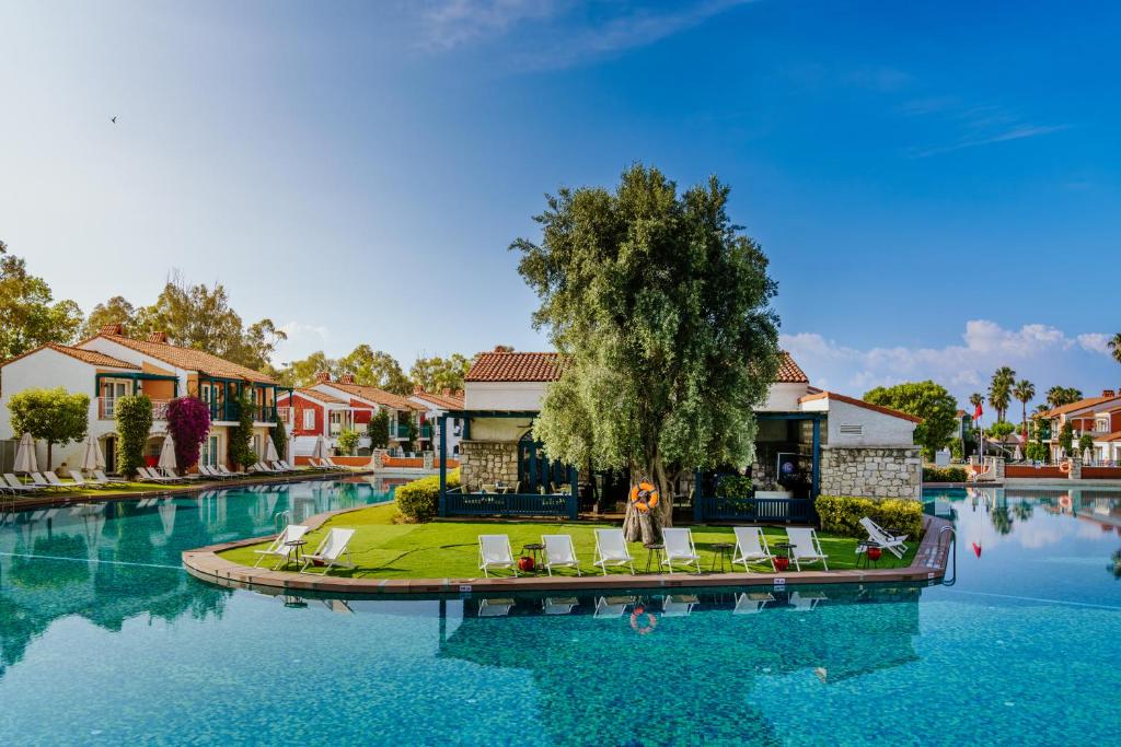 a resort with a swimming pool with chairs and a tree at IC Hotels Santai Family Resort - Kids Concept in Belek