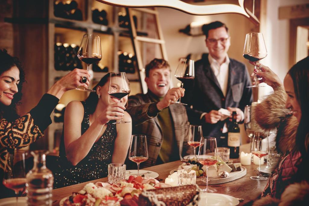 a group of people sitting around a table drinking wine at Burg Hotel Oberlech in Lech am Arlberg