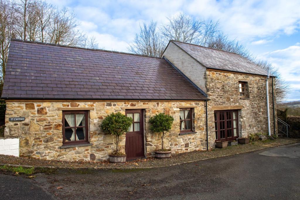 una antigua casa de piedra con techo marrón en Y Cartws Llanwenog en Llanwenog