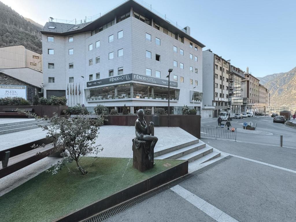 Une statue au milieu d'une ville avec un bâtiment dans l'établissement Fènix Hotel, à Andorre-la-Vieille