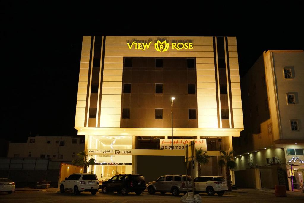 a view of a building with cars parked in a parking lot at view Rose Hotel Apartment in Dammam