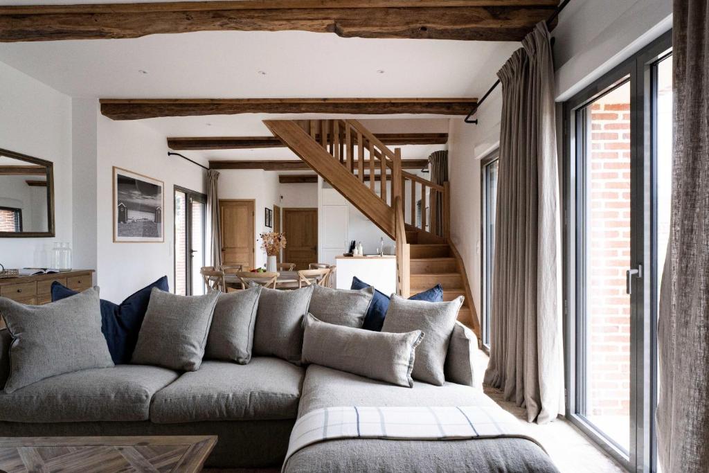 uma sala de estar com um sofá e uma escada em Maison Longere Beautiful House near Deauville em Cricquebœuf