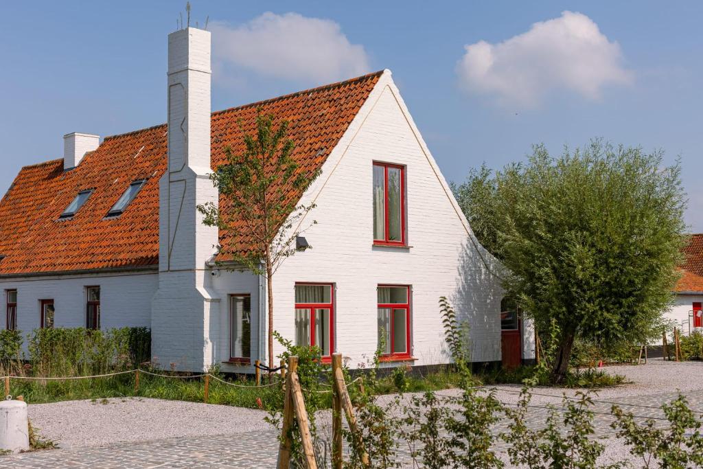 Cette maison blanche dispose d'une cheminée et de fenêtres rouges. dans l'établissement House at ranch between Bruges and Damme, à Bruges