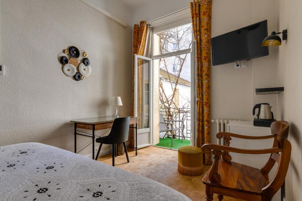 a bedroom with a bed and a table and a window at Hôtel Henri IV in Tarbes