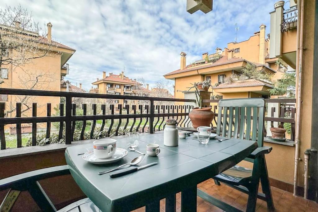a green table with cups and saucers on a balcony at [10 minuti dall'aeroporto] Linate Studio Flat in Peschiera Borromeo