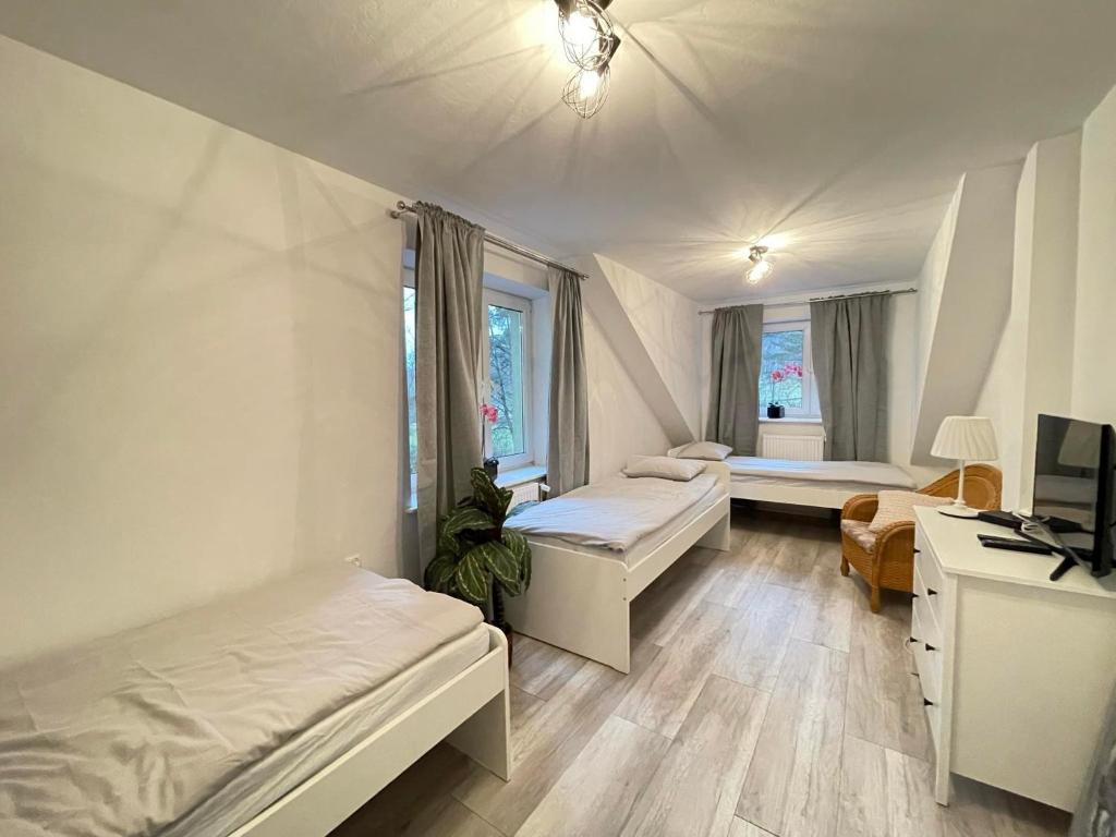 a bedroom with two beds and a desk and a tv at Ostoya Roztocze in Szczebrzeszyn