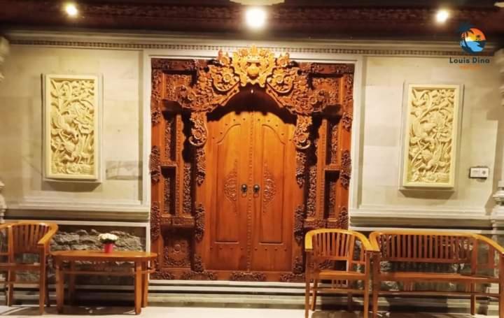 - une grande porte en bois dans une chambre avec des chaises dans l'établissement Dana guest house, à Ubud