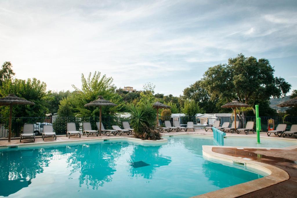 una gran piscina con sillas y sombrillas en Camping Lou Cabasson, en Bormes-les-Mimosas