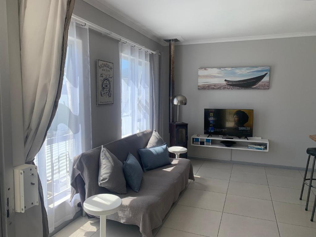 a living room with a couch and a tv at OysterCatcher Self-Catering Accommodation Strand in Cape Town