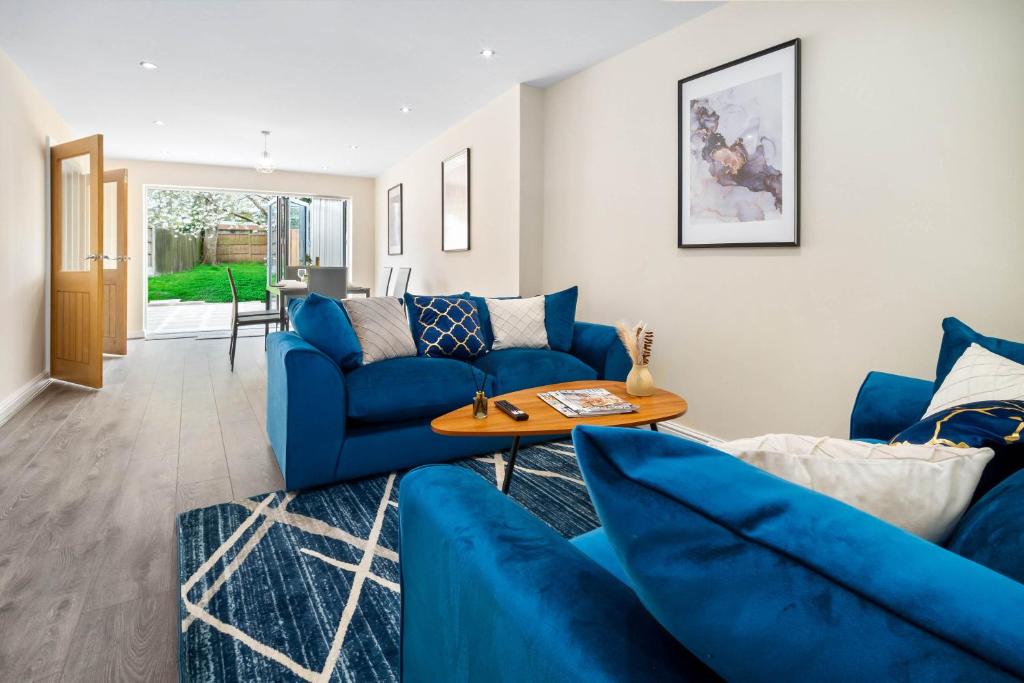 Luxury 4 Bedroom House - Harborne - Top Rated - Parking - Garden - 6CO في برمنغهام: غرفة معيشة مع أرائك زرقاء وطاولة
