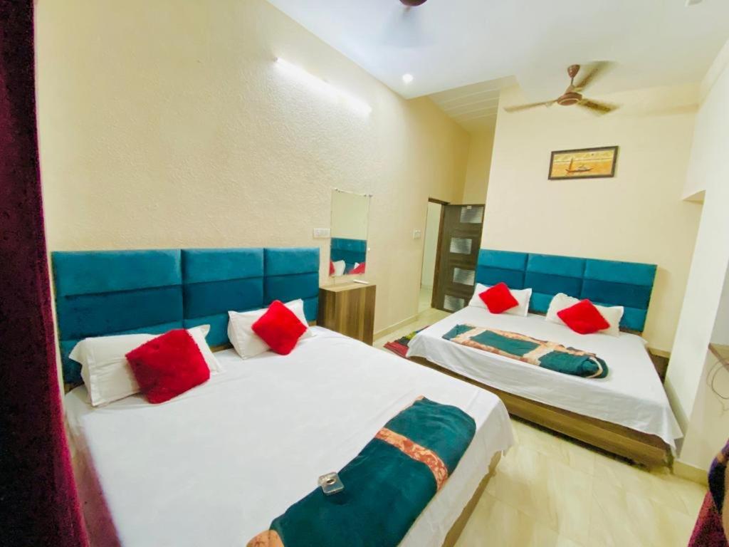 1 Schlafzimmer mit 2 Betten mit blauen und roten Kissen in der Unterkunft Arora classic guest house in Amritsar