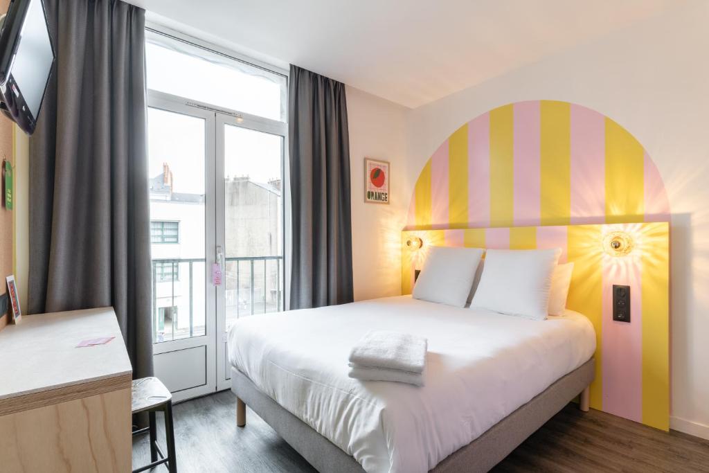 ein Hotelzimmer mit einem Bett und einem großen Fenster in der Unterkunft DEMAIN Hôtel & Conciergerie in Nantes