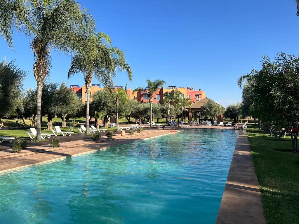 - une piscine dans un parc planté de palmiers dans l'établissement Appartement avec Solarium Privé au Vizir Résidence Prestigieuse avec Accès au Parc, à Marrakech