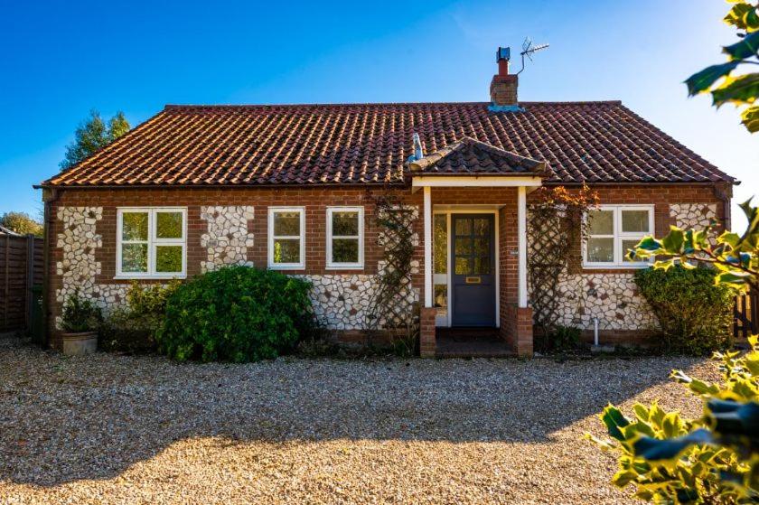 a small brick house with a blue door at Brambles in Brancaster