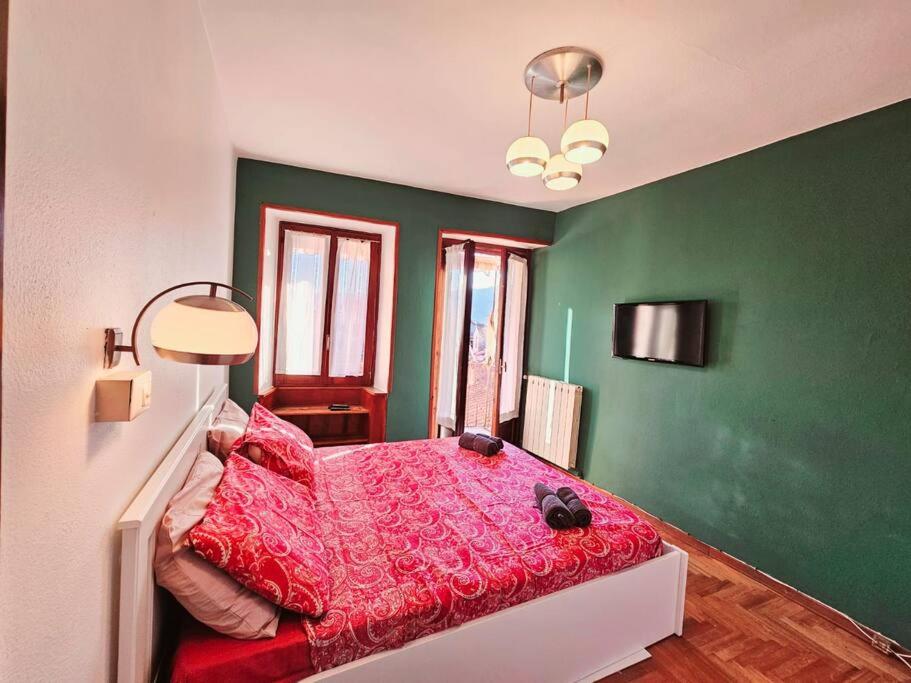 a bedroom with a red bed in a green wall at Clio Apartment in Verbania