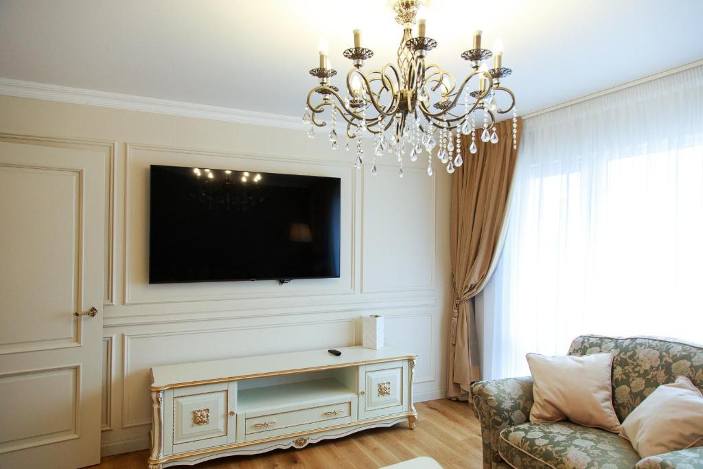 a living room with a chandelier and a tv at Boutique Apartments Kempes in Liepāja