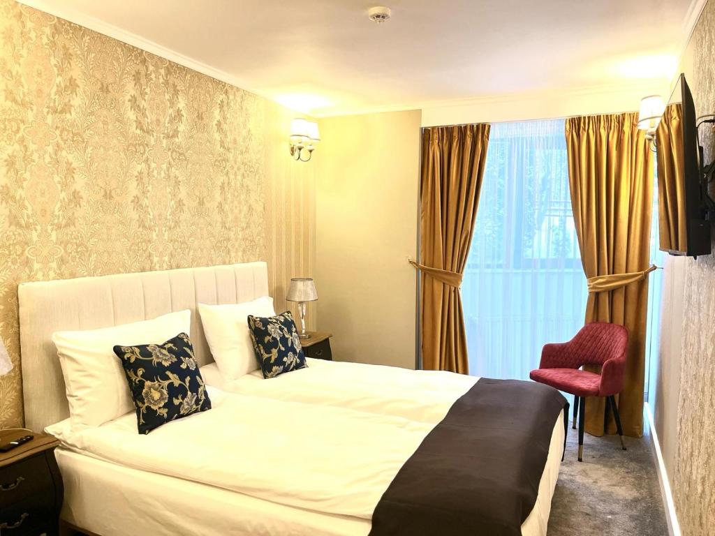 une chambre d'hôtel avec un lit et un fauteuil rouge dans l'établissement Torres Poiana, à Poiana Brasov
