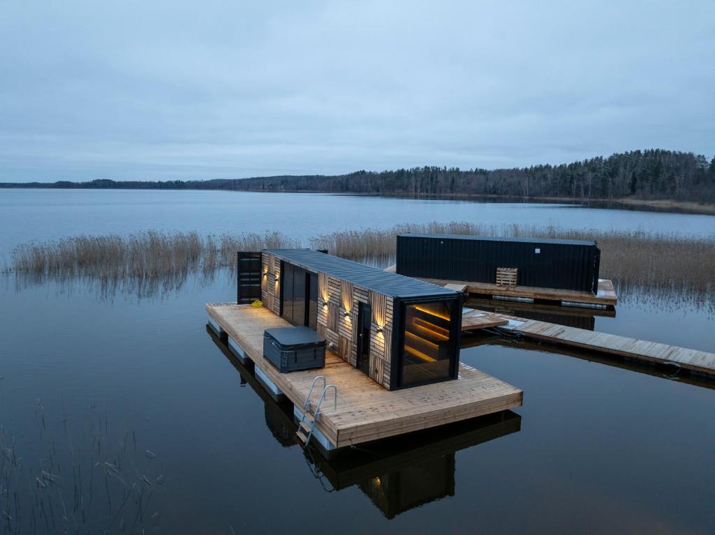 a tiny house on a dock on a body of water at ZEBRUS RESORT in Zebras Muiža