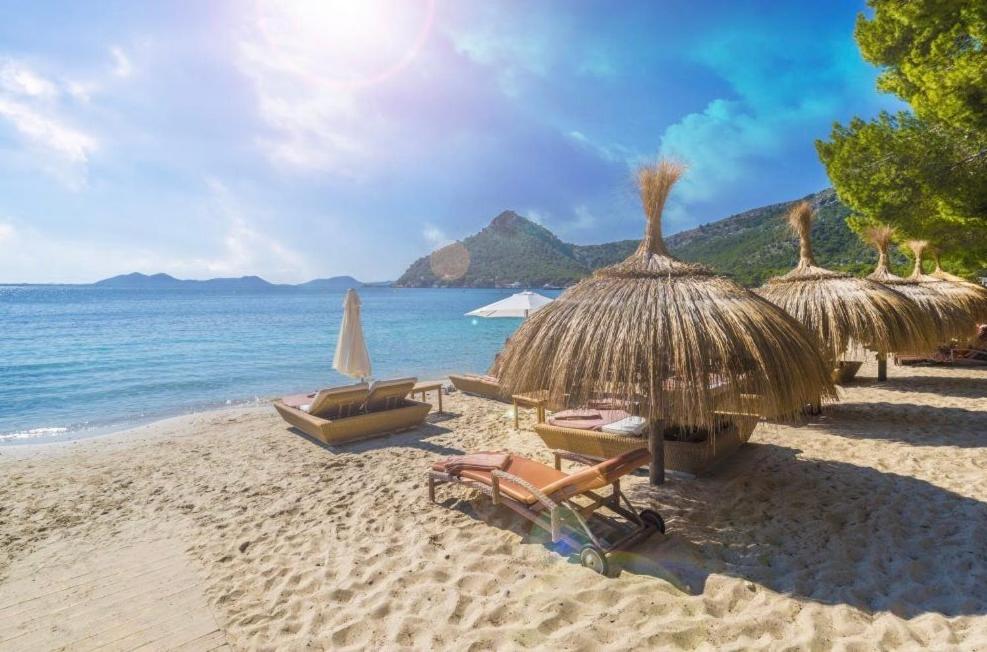 a beach with chairs and straw umbrellas and the ocean at APARTMENT MAGALUF in Torrenova