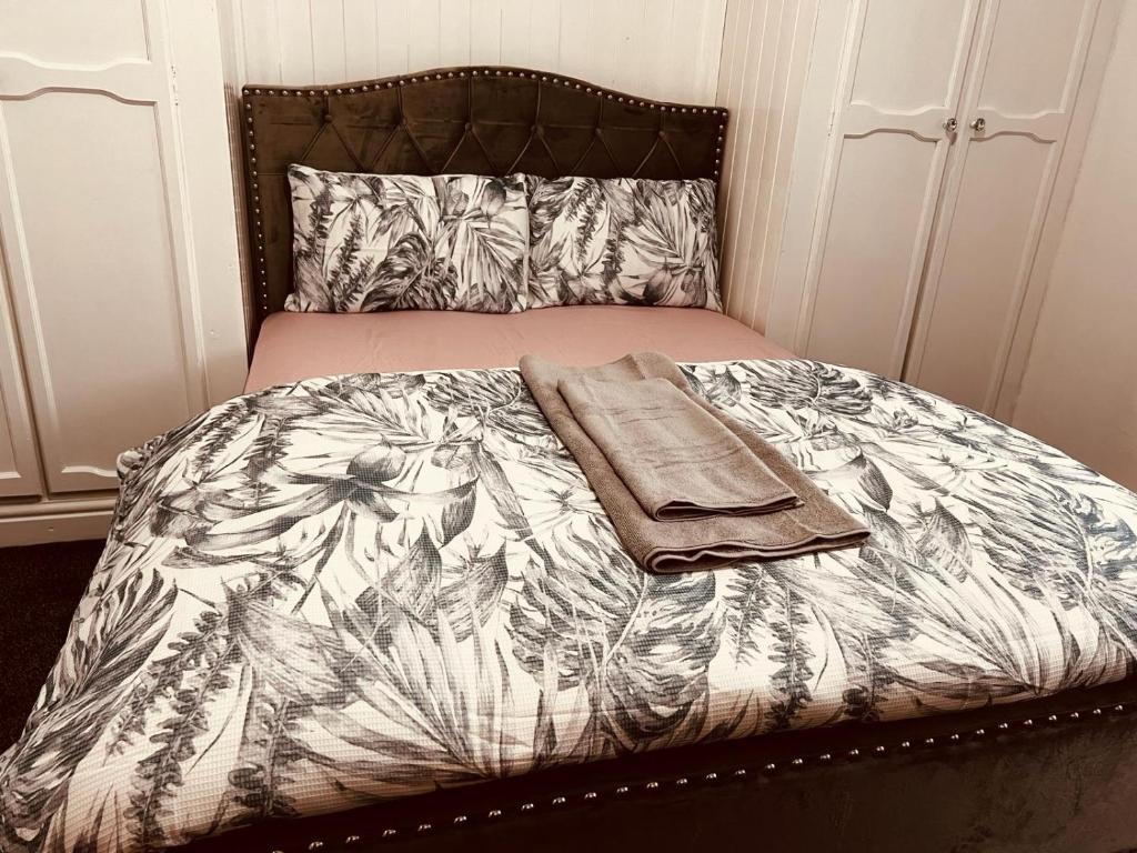 ein Bett mit einer Decke und zwei Handtüchern darauf in der Unterkunft Holiday House Near Football Ground in Nottingham