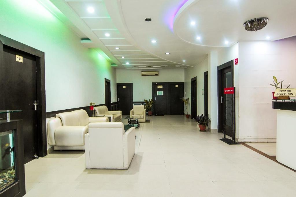 vestíbulo con sillas blancas y sala de espera en OYO Hotel Indiana Near Gomti Riverfront Park, en Vibhuti Khand