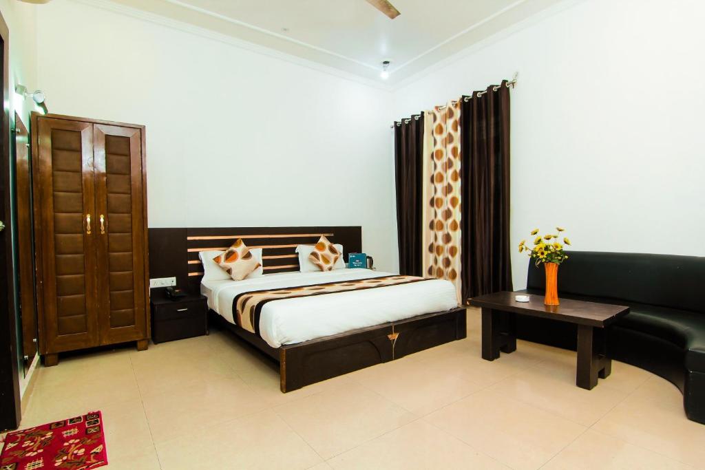 um quarto com uma cama, um sofá e uma mesa em OYO Hotel Indiana Near Gomti Riverfront Park em Vibhuti Khand