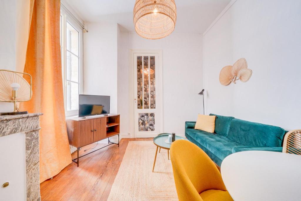 un salon avec un canapé bleu et une télévision dans l'établissement Le New Vintage - Appt en plein cœur de Bordeaux, à Bordeaux