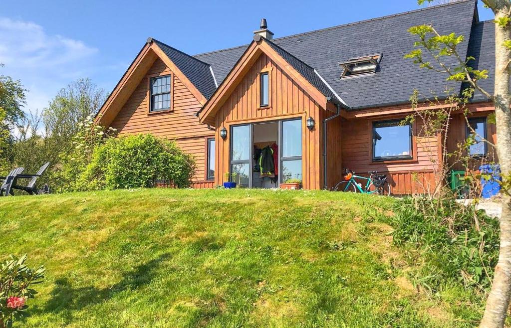 une maison en bois avec une grande pelouse devant elle dans l'établissement Laimhrig, à Torrin