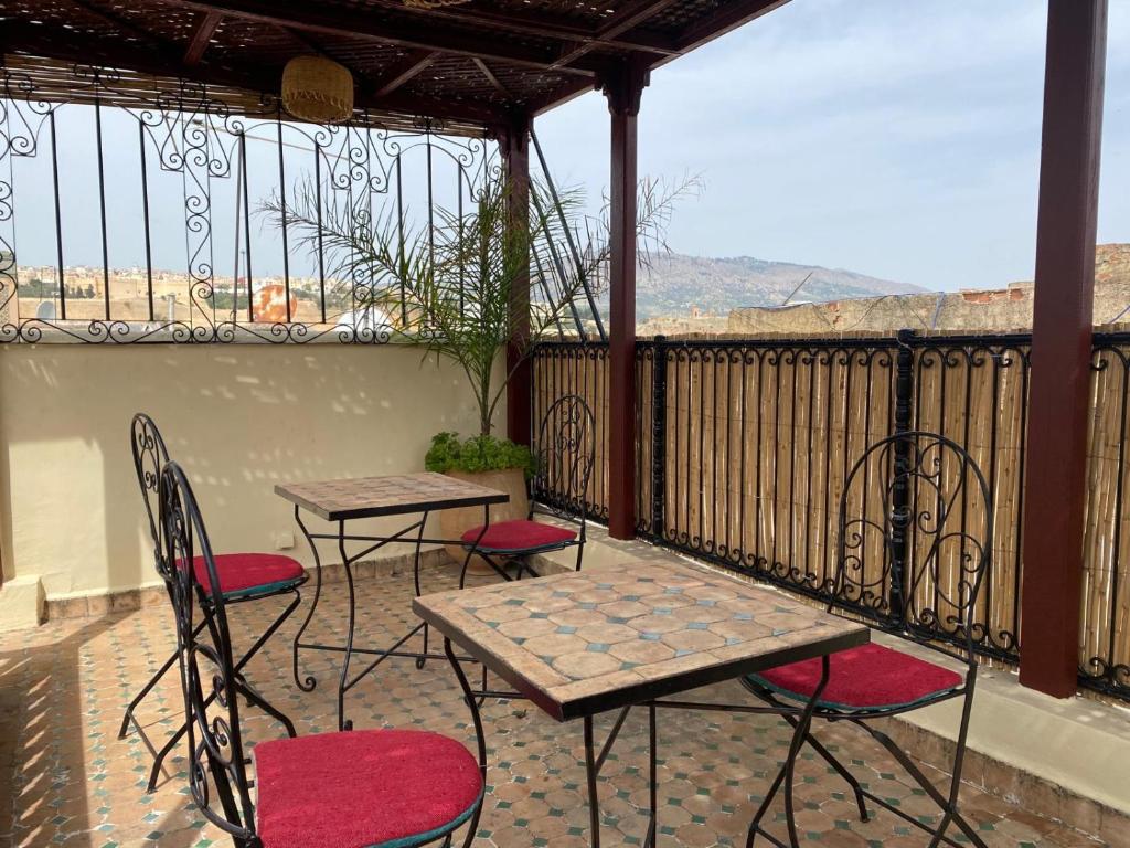 a patio with two tables and chairs on a balcony at Charmant Ryad à 1mn de BAB BOUJLOUD DAR SERRAJ in Fez