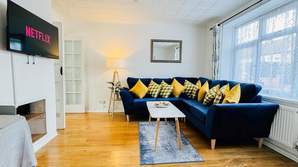 a living room with a blue couch and yellow pillows at "The Cromwell" I Contractor's Haven Borehamwood I 3 - 6 Beds I Free Parking, Netflix & Sky Sports in Borehamwood