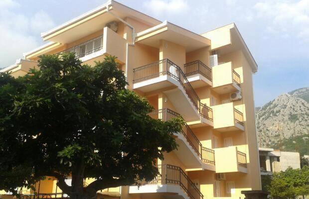 a building with balconies and a tree in front of it at Apartments Percobic in Sutomore