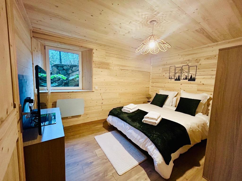 een slaapkamer met een bed en een kroonluchter bij Au P'tit Randonneur avec terrasse - CLG - 1CH - 1 SDB in Chevillard