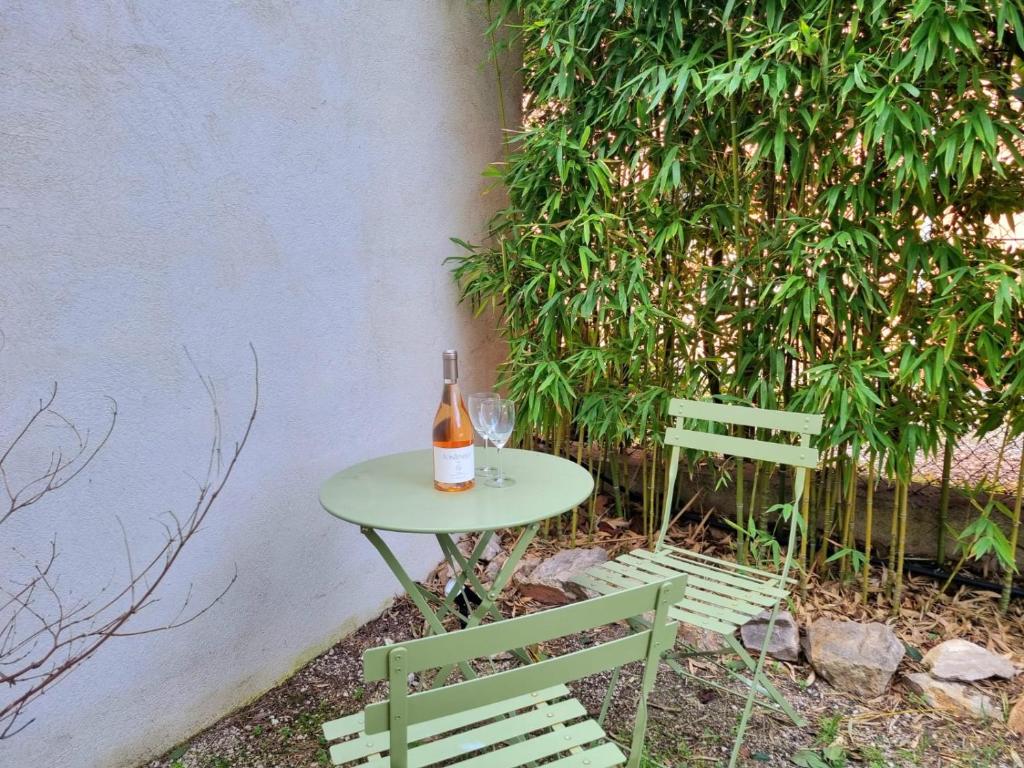 a table with a bottle of wine and two chairs at Joli studio lumineux centre avec parking securise dans quartier recherche in Aix-en-Provence