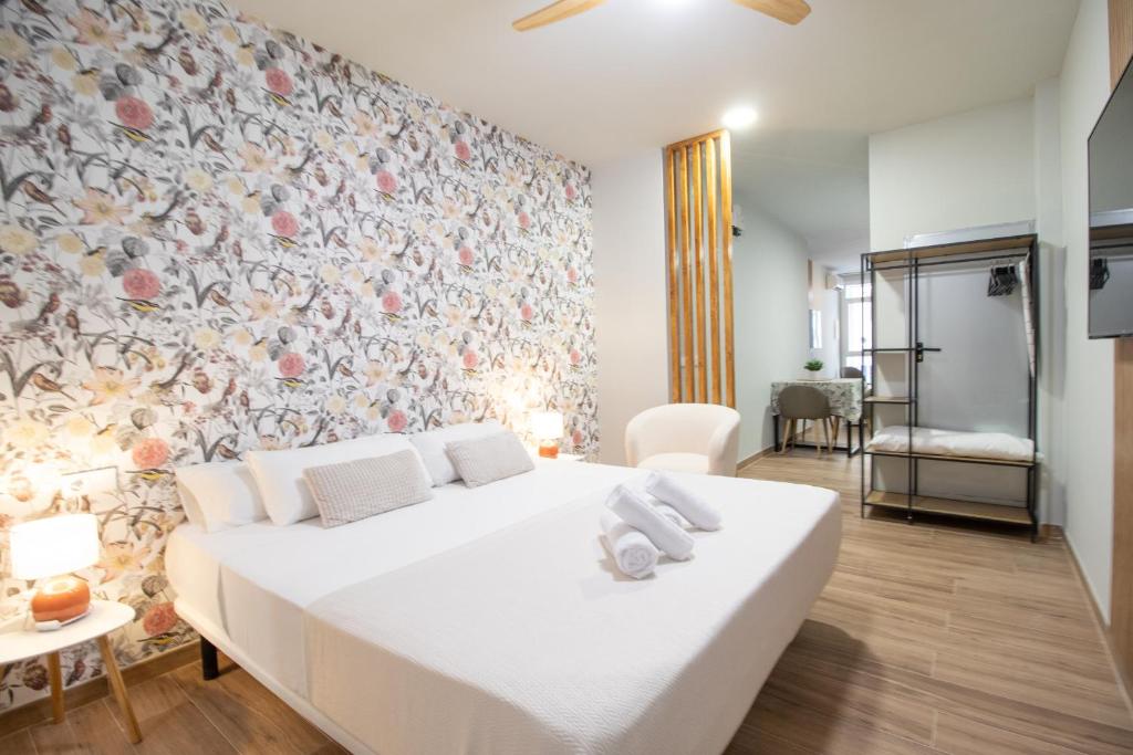 a white bed in a room with a floral wall at Suite Parque del Turia by Clink in Valencia