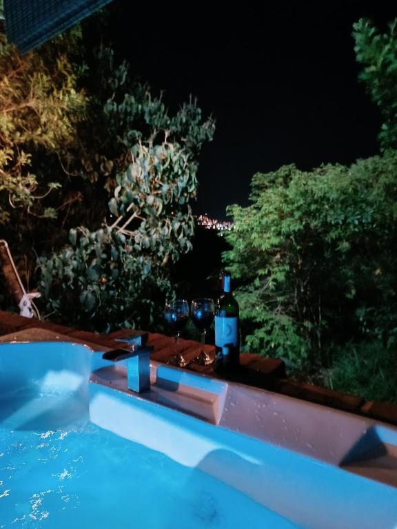 una bottiglia di vino seduta sul bordo della piscina di notte di Glamping el nido a Curití