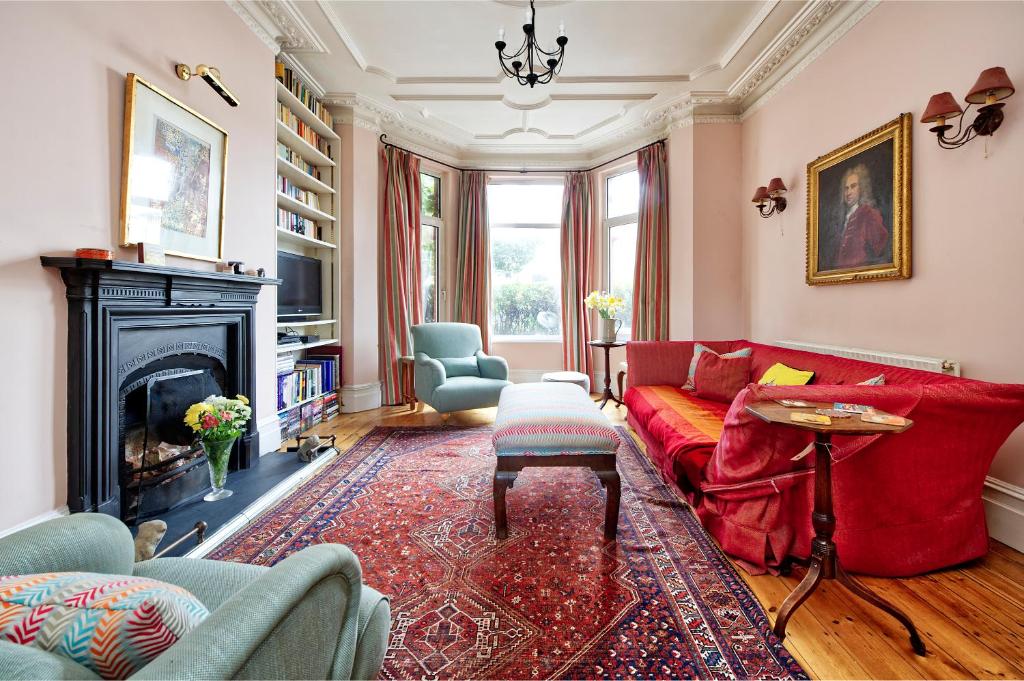 a living room with a red couch and a fireplace at Veeve - Vividly Vintage in London