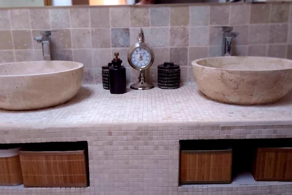un baño con dos lavabos y un reloj en una encimera en Charmante maison de village, en Mondragon