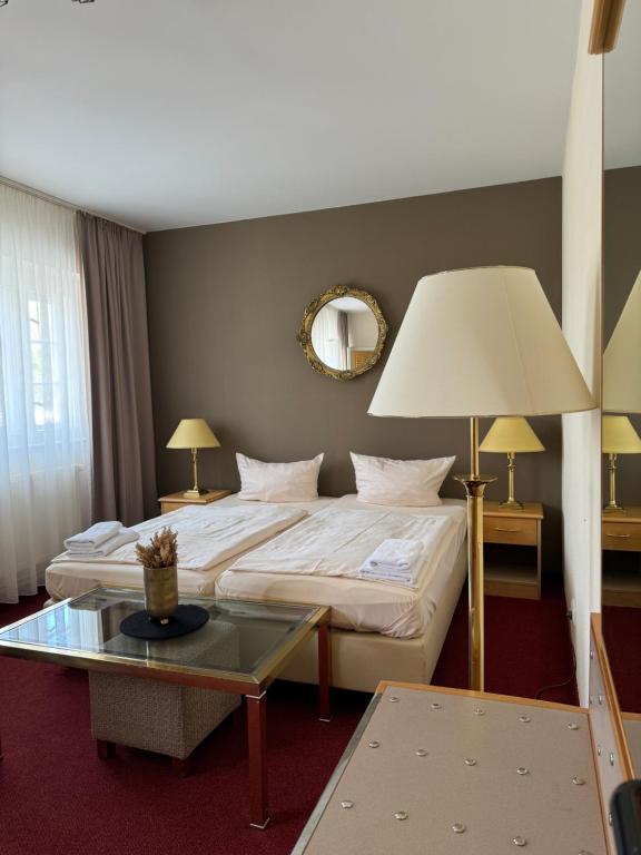 ベルリンにあるHotel Bonverde (Wannsee-Hof)のベッドとテーブルが備わるホテルルームです。