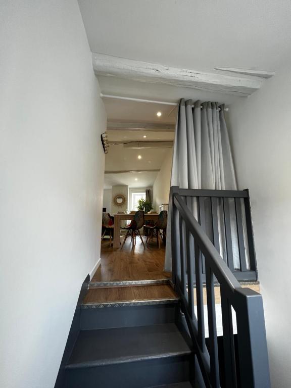 uma escada que leva a uma sala de estar com uma cortina em La maison castelpontine T4 em Pont-du-Château